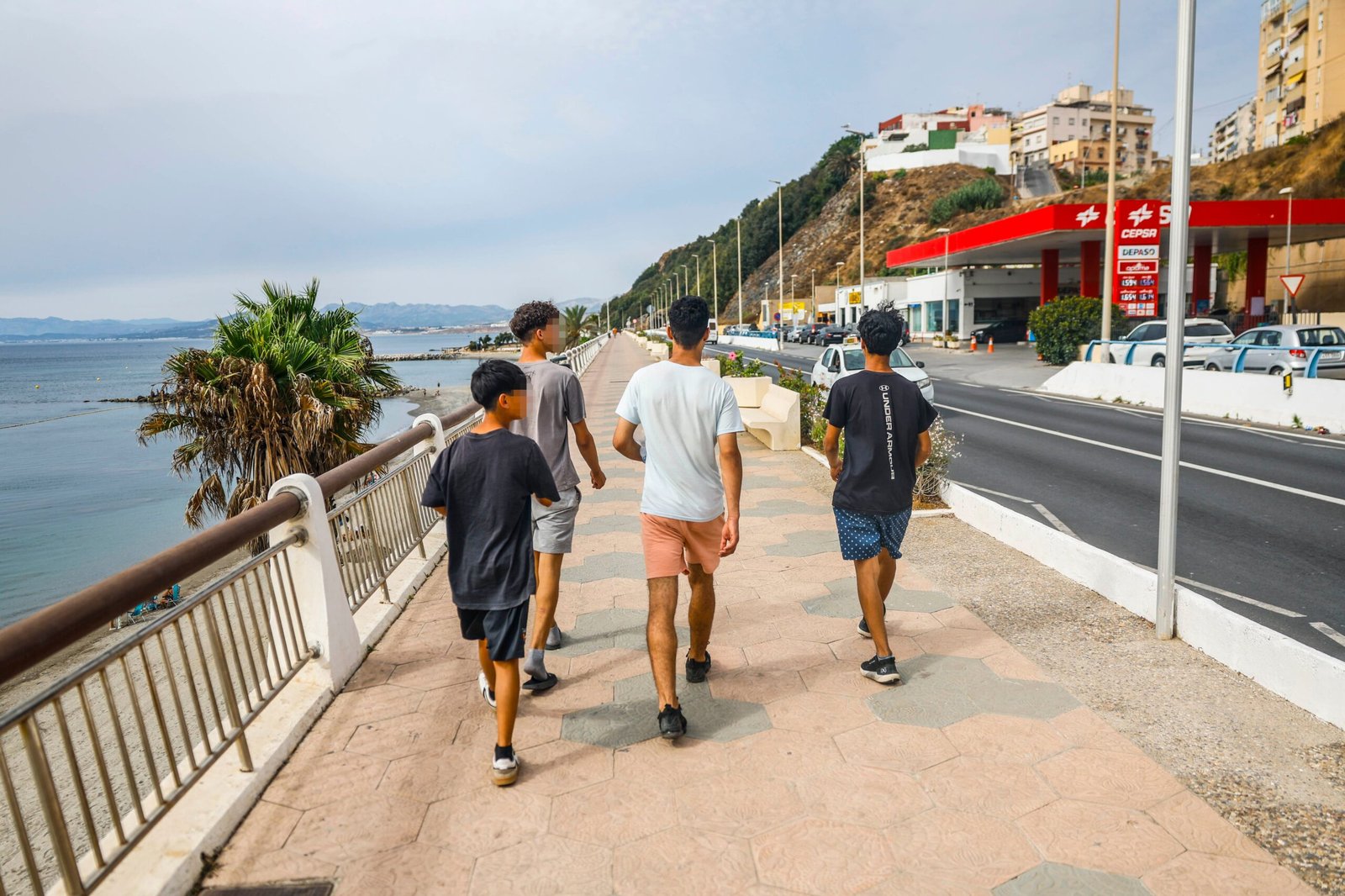 Cuatro menores migrantes caminan por el paseo marítimo de Ceuta.